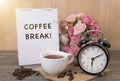 Hot cup of coffee and alarm clock on wood table with rose flower Royalty Free Stock Photo