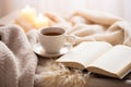 Hot cup of coffee and open book surrounded by a fluffy blanket on bed on a cold winter day. Relaxation and hygge concept Royalty Free Stock Photo