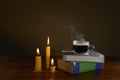 A hot cup of coffee with smoke, books, and burning candles Royalty Free Stock Photo