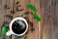 Hot cup of coffee with smoke, coffee beans and green leaves on vintage wooden background Royalty Free Stock Photo