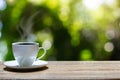 Hot cup of coffee on wooden tabletop on blurred green nature bokeh background Royalty Free Stock Photo