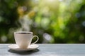 Hot cup of coffee on wooden tabletop on blurred green nature bokeh background Royalty Free Stock Photo