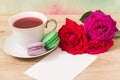 Hot cup of tea, colored cakes and pink flower Royalty Free Stock Photo