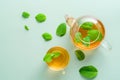 Hot cup of tea and teapot with mint on green background. Flat lay, top view. Herbal tea concept Royalty Free Stock Photo
