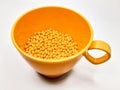 hot cut type orange masterbatch granules on same colored plastic cup, isolated white background Royalty Free Stock Photo