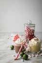 Hot dark chocolate during holiday season with whipped cream, marshmallows, candy canes, Christmas tree ornaments, green glitter Royalty Free Stock Photo