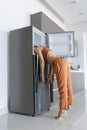 On a hot day, the girl cools with his head in the refrigerator. Broken air conditioner Royalty Free Stock Photo