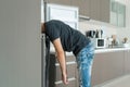 On a hot day, the guy cools with his head in the refrigerator. Broken air conditioner Royalty Free Stock Photo