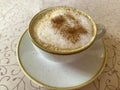 Hot delicious cappuccino with foam and cinnamon in vintage cup on table Royalty Free Stock Photo