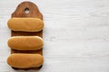 Hot dog buns on a rustic wooden board on a white wooden surface, top view. Flat lay, from above, overhead. Copy space Royalty Free Stock Photo