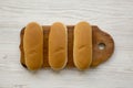 Hot dog buns on wooden board on white wooden background, top view. Flat lay, from above, overhead.