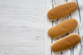 Hot dog buns on wooden board on white wooden background, top view. Flat lay, from above, overhead Royalty Free Stock Photo