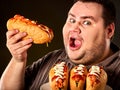 Hot dog contest. Fat man eating fast food hot dog.
