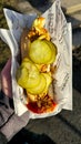 Hot dog with cucumbers, roasted snacks, mustard, ketchup, sausage, rolls in hand Royalty Free Stock Photo