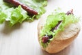 Hot dog. Grilled hot dogs with fresh salad lettuce on wooden table.