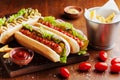 Hot dog with grilled sausage, ketchup, mustard and fries on wooden kitchen board. Traditional american fast food. Royalty Free Stock Photo