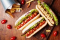 Hot dog with grilled sausage, ketchup, mustard and fries on wooden kitchen board top view. Traditional american fast food. Royalty Free Stock Photo