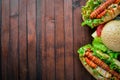 Hot dog and hamburger with cheese, meat and greens on Wooden background. Royalty Free Stock Photo