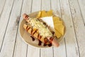 Hot dog with Mexican chili sauce, cheddar cheese and shredded cheese garnished