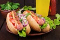 Hot dog with sausage, cucumber, tomato and lettuce on dark wooden background. Royalty Free Stock Photo