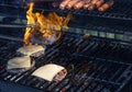 Hot dogs and cheeseburgers being grilled with flames covering one Royalty Free Stock Photo