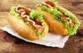 Hot dogs with lettuce,tomatoes and cucumber on tray on wooden board