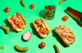 Hot dogs with vegetables, mustard and ketchup on a bright green background. Cucumbers and tomatoes, drink in a glass. Bright Royalty Free Stock Photo