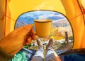 Hot drink in the hand and wonderful view of colorful autumn mountain tops through the open entrance to the tent. The beauty of a Royalty Free Stock Photo