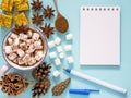 Hot drink with marshmallow and and notebook on blue background Royalty Free Stock Photo