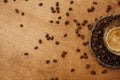 Hot espresso with foam in glass cup on vintage plate with aromatic roasted coffee beans on wooden table. Flat lay with copy space