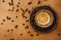 Hot espresso with foam in glass cup on vintage plate with aromatic roasted coffee beans on wooden table. Flat lay with copy space