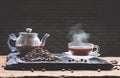 Hot espresso in glass coffee cup with steam and coffee pot on wooden table with black brick wall background in vintage style Royalty Free Stock Photo