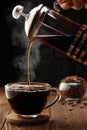 espresso pouring from french press coffee maker into glass cup on wooden table with black background Royalty Free Stock Photo