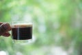 Hot espresso shots in handle glass in hand