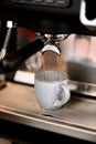 Hot fragnant espresso pouring in small white cup, close up view. Process of making coffee Royalty Free Stock Photo