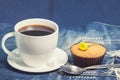 Hot fresh coffee in white cup and soft cake on blue jeans on tab Royalty Free Stock Photo