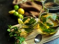 Hot and fresh cup of mint tea, lemon, spoon and glass tea pot Royalty Free Stock Photo
