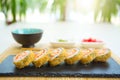 Hot fried Sushi Roll with cream cheese on black stone on bamboo mat decorated. Japanese cuisine Royalty Free Stock Photo