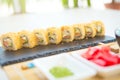 Hot fried Sushi Roll with cream cheese on black stone on bamboo mat decorated. Japanese cuisine Royalty Free Stock Photo