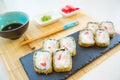 Hot fried Sushi Roll with cream cheese on black stone on bamboo mat decorated. Japanese cuisine Royalty Free Stock Photo