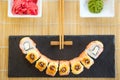 Hot fried Sushi Roll with cream cheese on black stone on bamboo mat decorated. Japanese cuisine. Smile Royalty Free Stock Photo