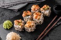 Hot fried Sushi rolls and maki set with smoked eel, cream cheese, avocado, caviar and wasabi on black slate background. Royalty Free Stock Photo