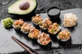 Hot fried Sushi rolls and maki set with smoked eel, cream cheese, avocado, caviar and wasabi on black slate background. Royalty Free Stock Photo