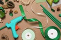 Hot glue gun and handicraft materials on brown background, flat lay