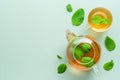 Hot green tea with mint in teapot and cup on green background. Herbal tea concept. Flat lay, top view Royalty Free Stock Photo