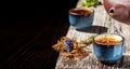 Hot green tea is poured from the teapot into the blue bowl, vintage wooden table, steam rises above the cup. Tea leaves next to