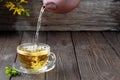 Hot green tea is poured from the teapot into the glass bowl, vintage wooden table, steam rises above the cup. Tea leaves next to Royalty Free Stock Photo