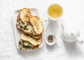 Hot grilled tomatoes, spinach, mozzarella sandwiches and green tea - healthy breakfast, snack on a light background