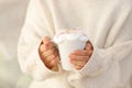 Hot hands holding a white mug with cream topping