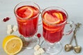 Hot healthy cranberry tea or detox winter drink - sangria with fresh lemons in glasses on the gray concrete background